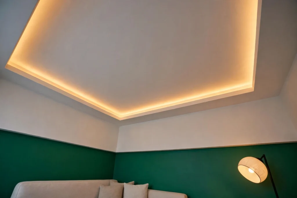 Shallow tray false ceiling with recessed LED cove lighting in a small living room with emerald walls