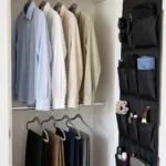 Small closet organized with slim hangers, a double hanging rod and labeled top-shelf boxes